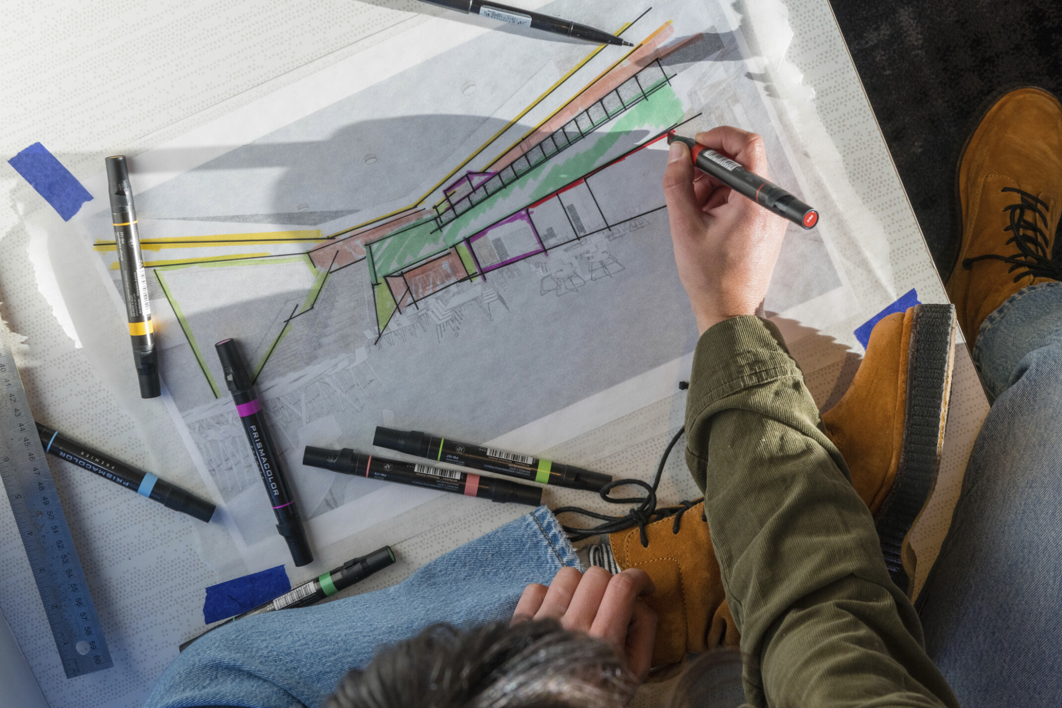 overhead view of woman drawing on an architectural plan