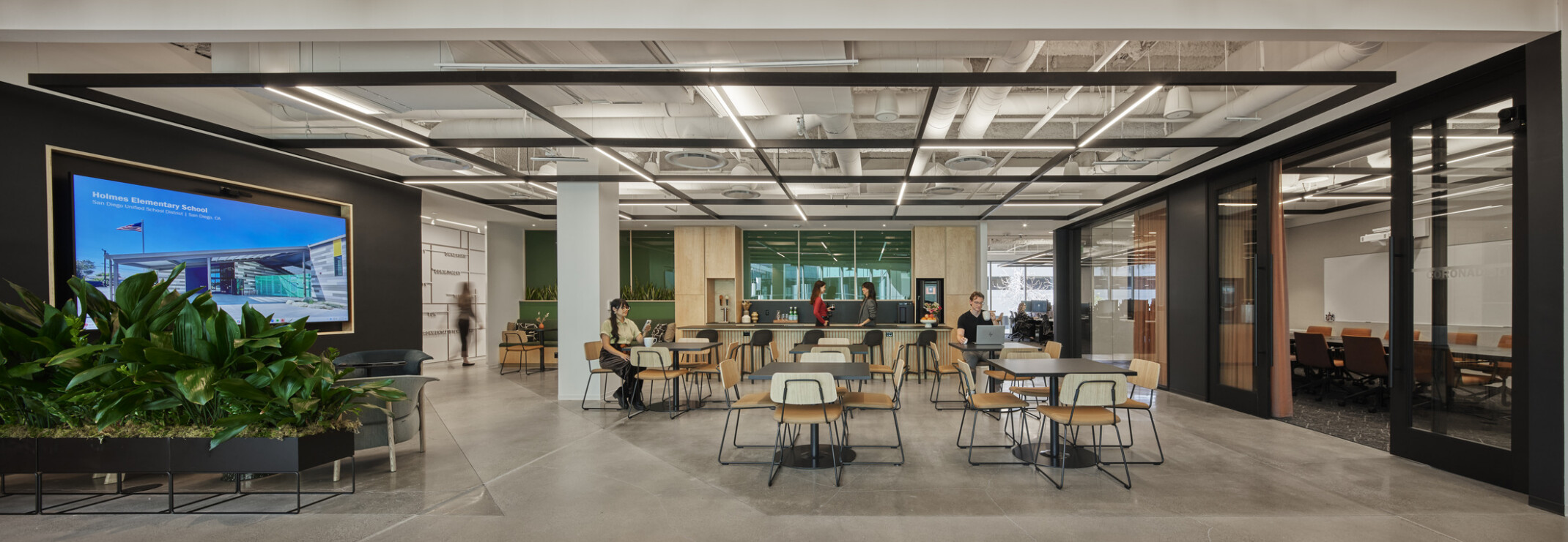 modern office interior with a dark green accent wall, light wood accents, and tables for staff
