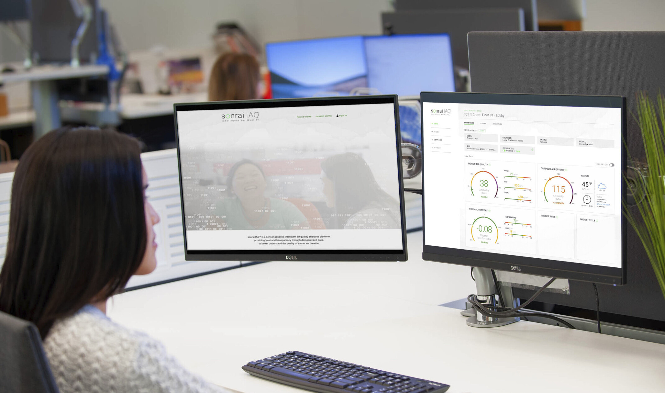 woman with 2 monitors looking at IAQ data on right screen and sonrai website on left at white desk in office
