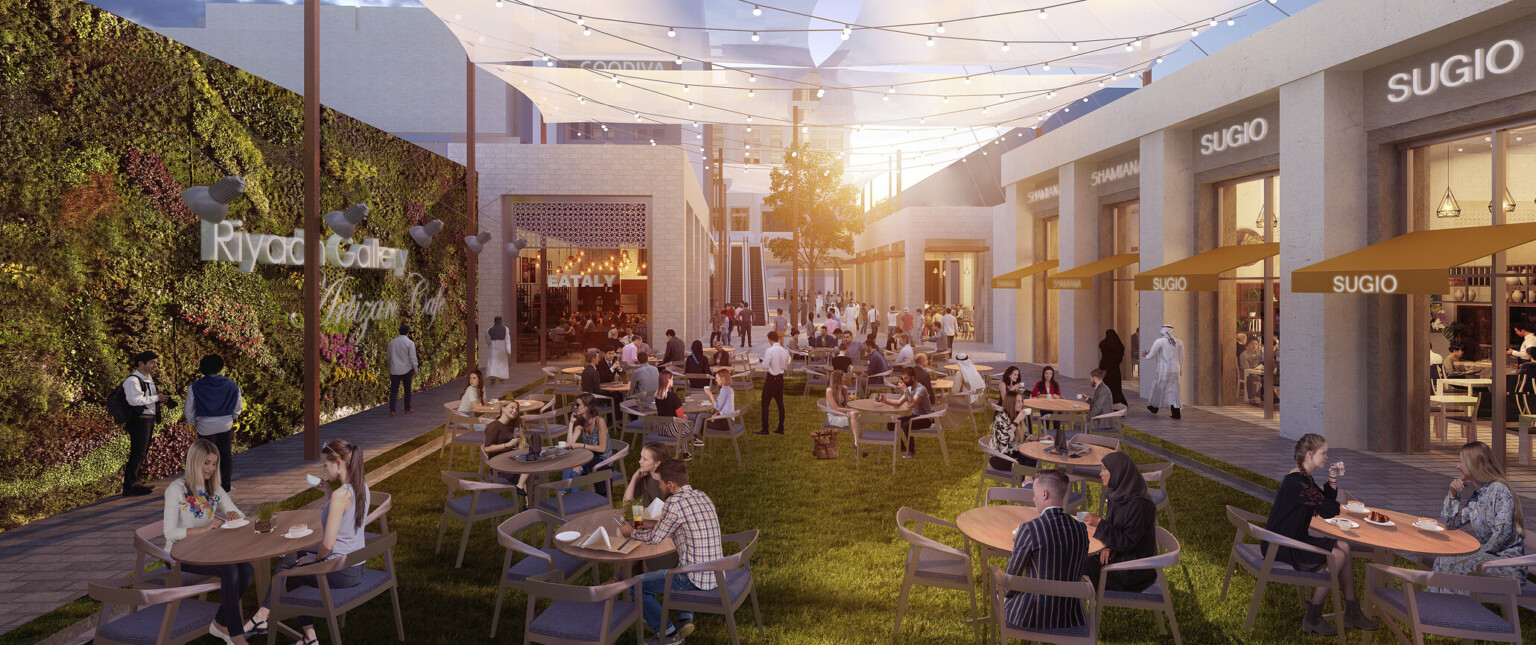 Outdoor seating area at the Riyadh Gallery showing patrons sitting at tables with a wall of lush greenery