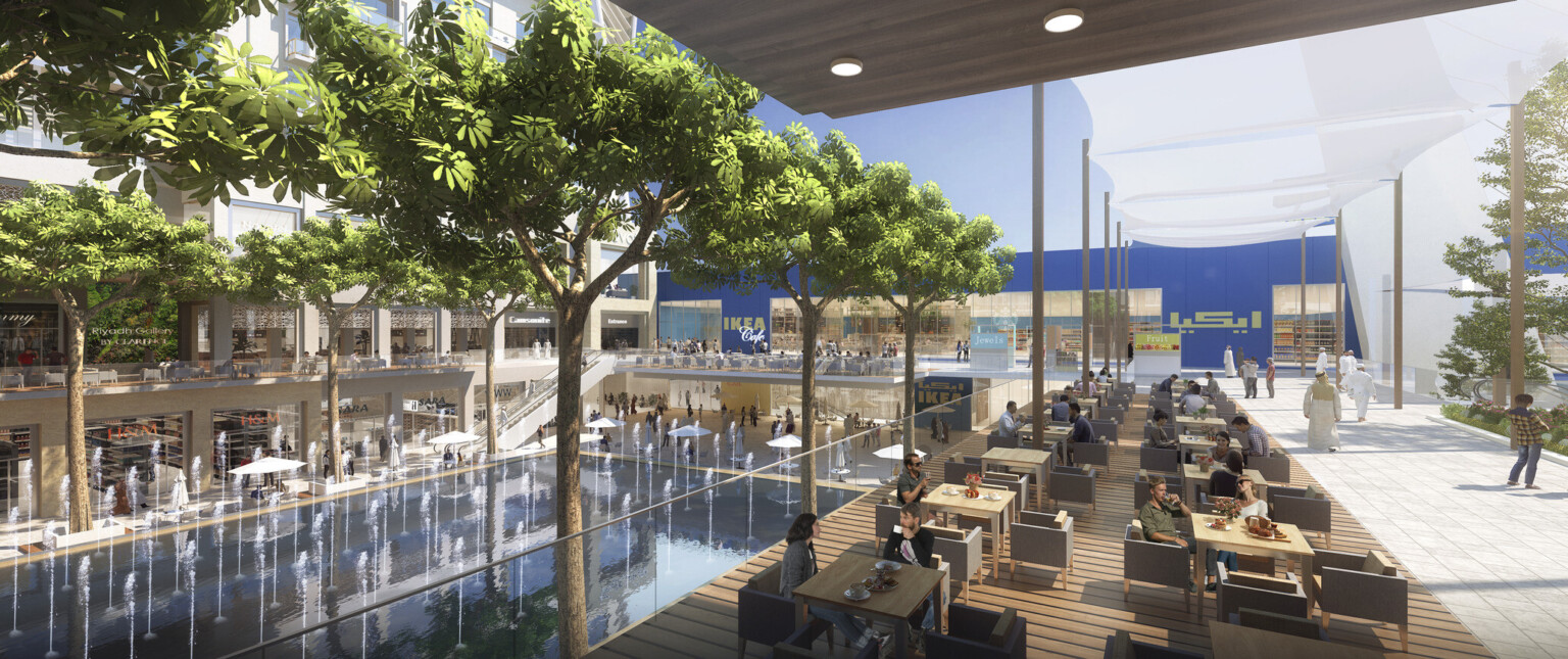 Exterior of an outdoor mall showing seatings areas with a large water fountain in front of a blue wall