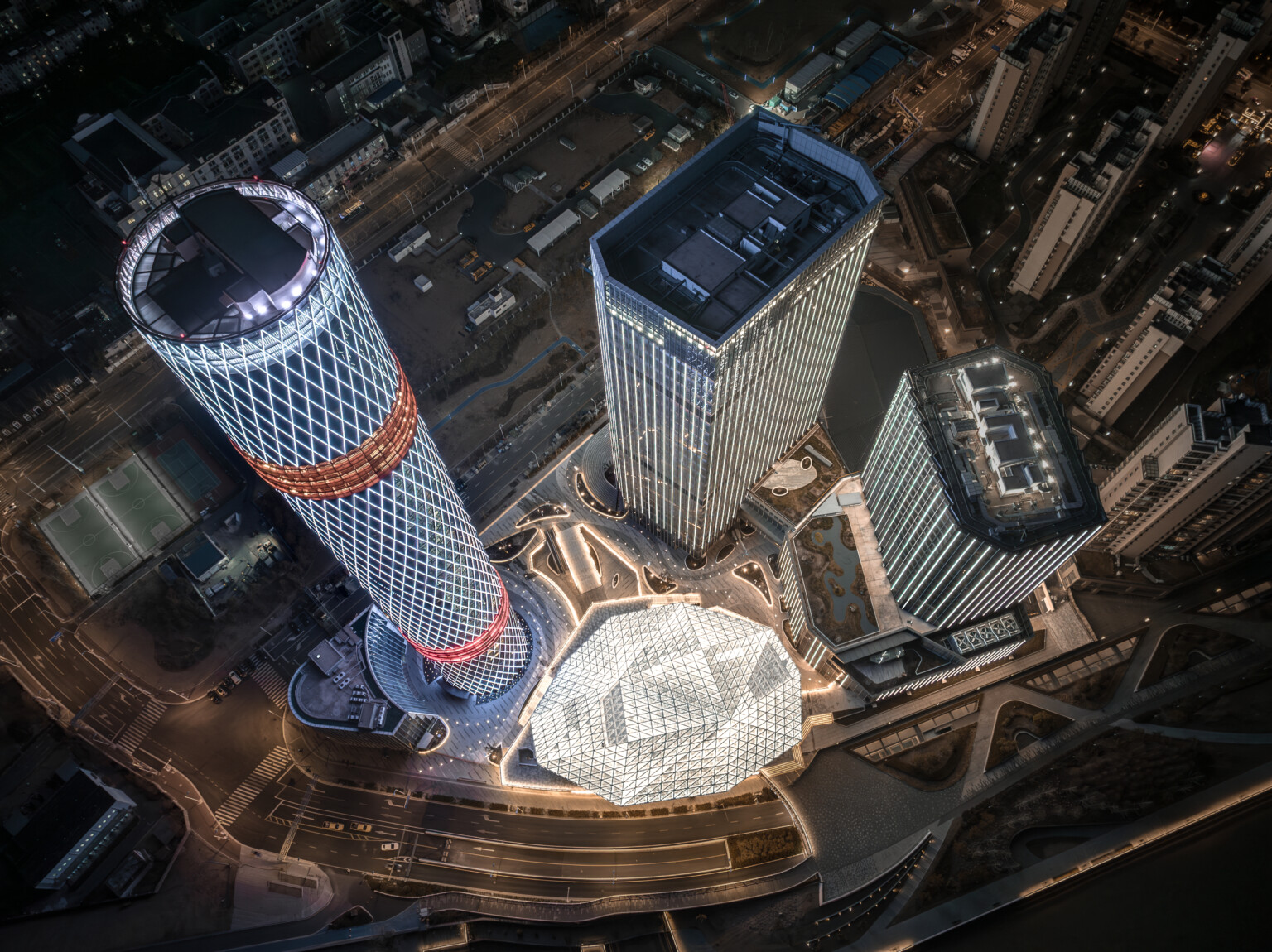 Complex viewed from above buildings illuminated with geometric triangular and diamond shaped panels red light bands on tower