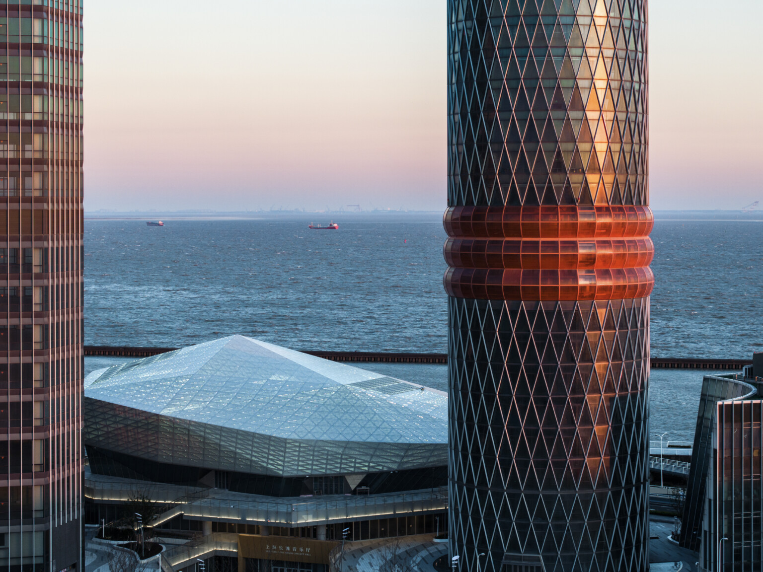 side view of tower with three red bands, view of diamond shaped angular arts building and river beyond