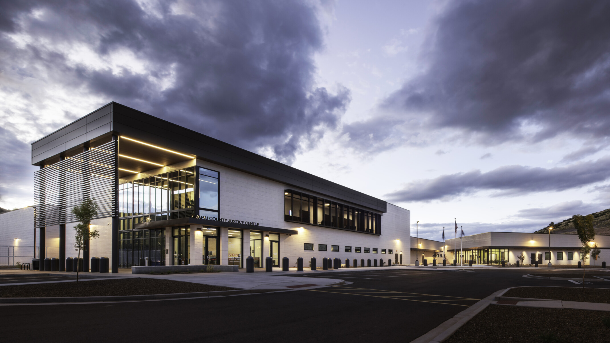 Yavapai County Criminal Justice Center exterior with large windows, canopied wrap facade, illuminated in the evening