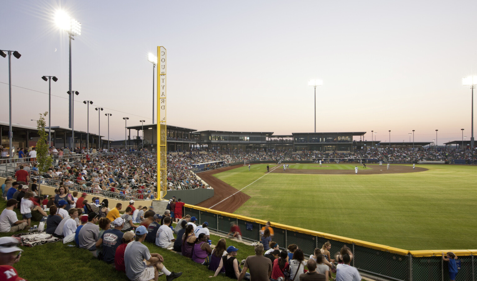 Lower deck seating at right field with yellow perforated metal foul line labeled Courtyard. View of box seats by home plate