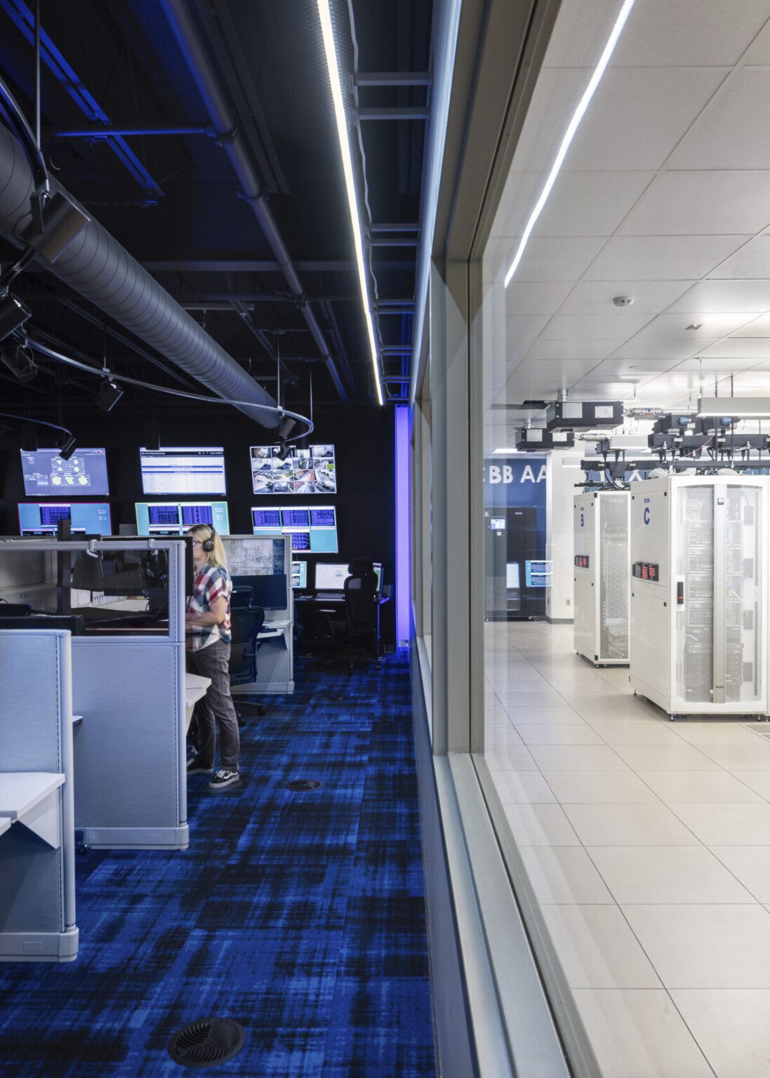 server data center shows temperature-controlled area behind tempered glass and call center area where technicians work to keep servers up and take service calls from customers