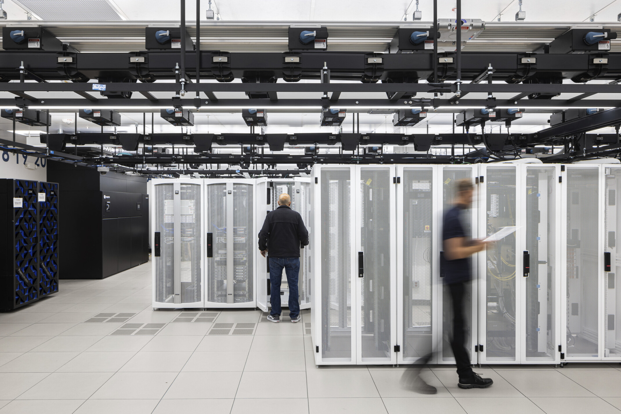 White data center racks set against pops of black storage and ceiling treatment provide a minimalist look and feel to the data storage room