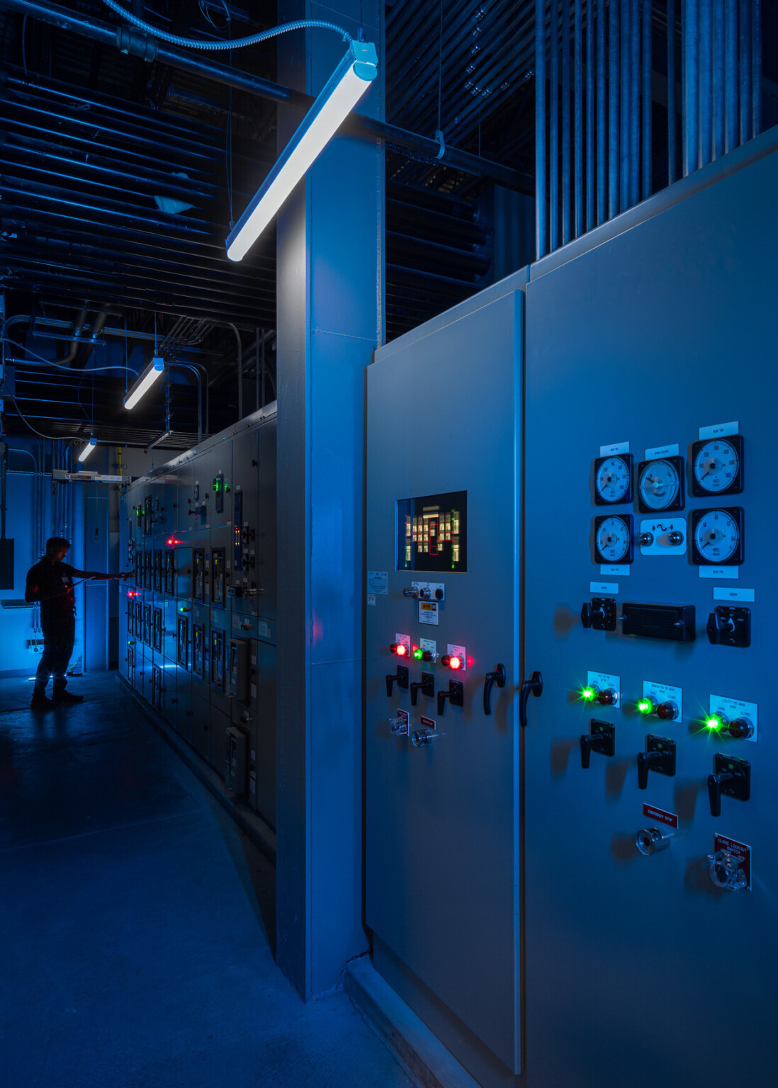 close-up of blue lighted master server panel in data center, engineer adjusting settings in the background