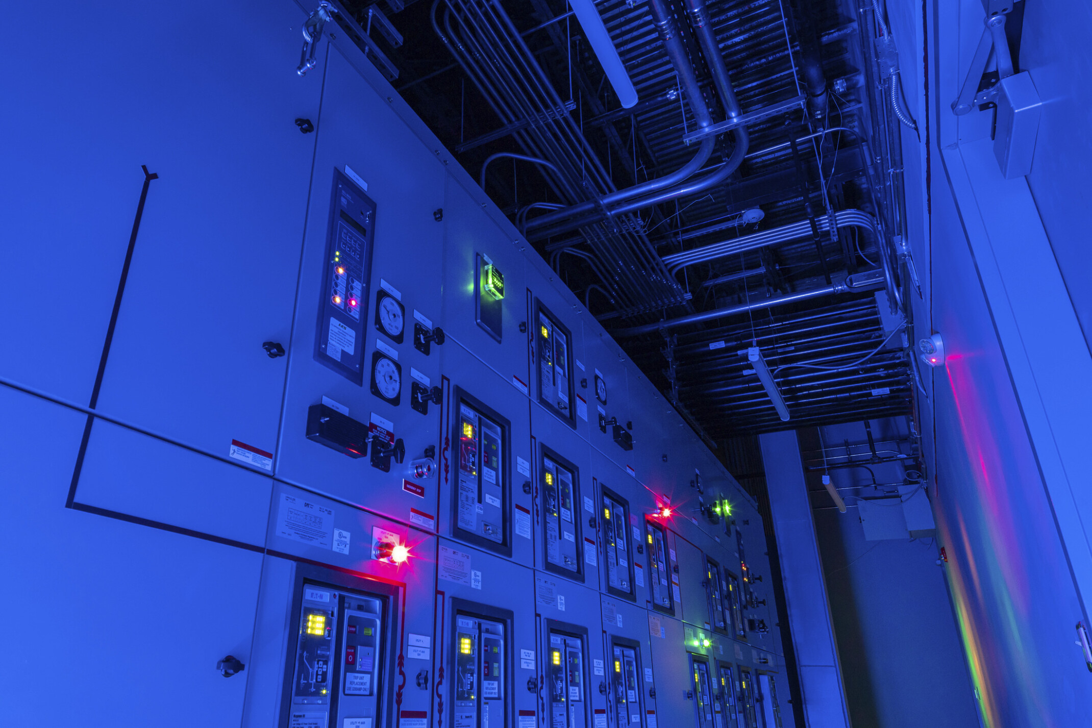 Red and green lights illuminating in a blue control panel displaying numerous switches and lights