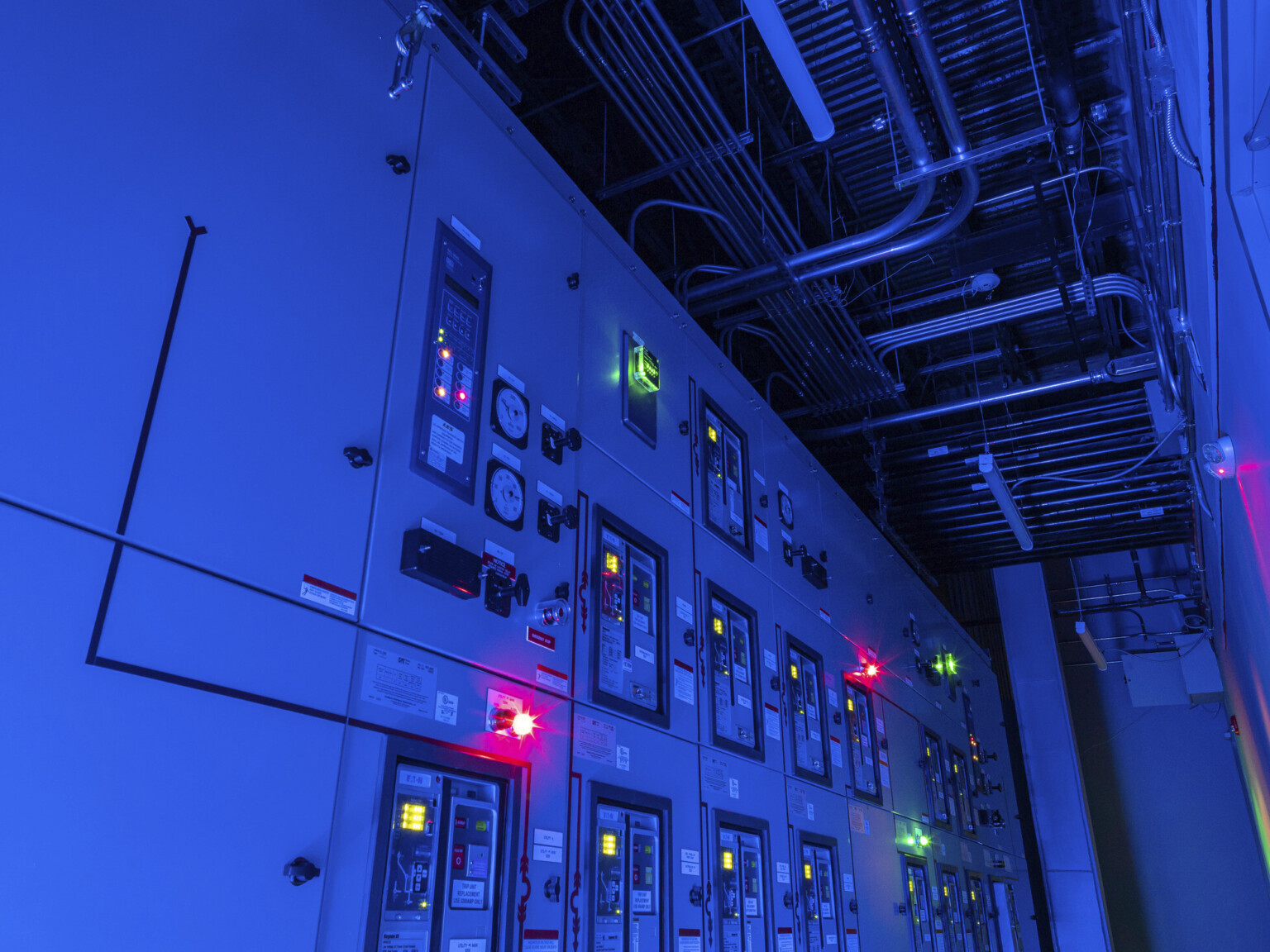 Red and green lights illuminating in a blue control panel displaying numerous switches and lights