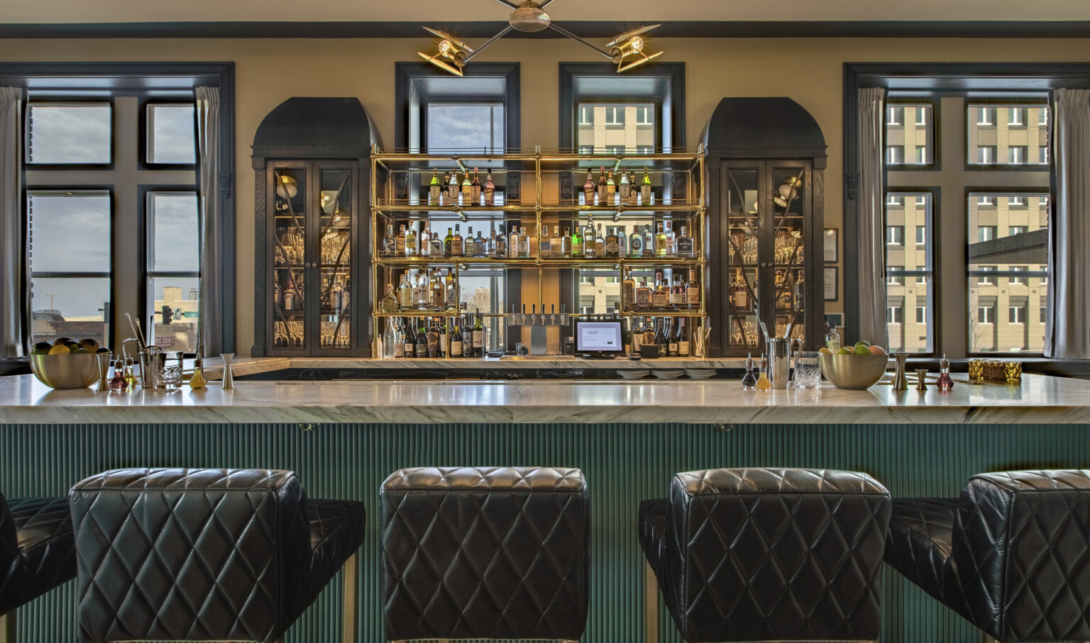 a marble topped bar with quilted leather stools