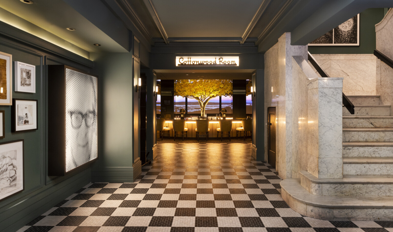 a marble staircase and gallery wall flank a black and white checkered floor