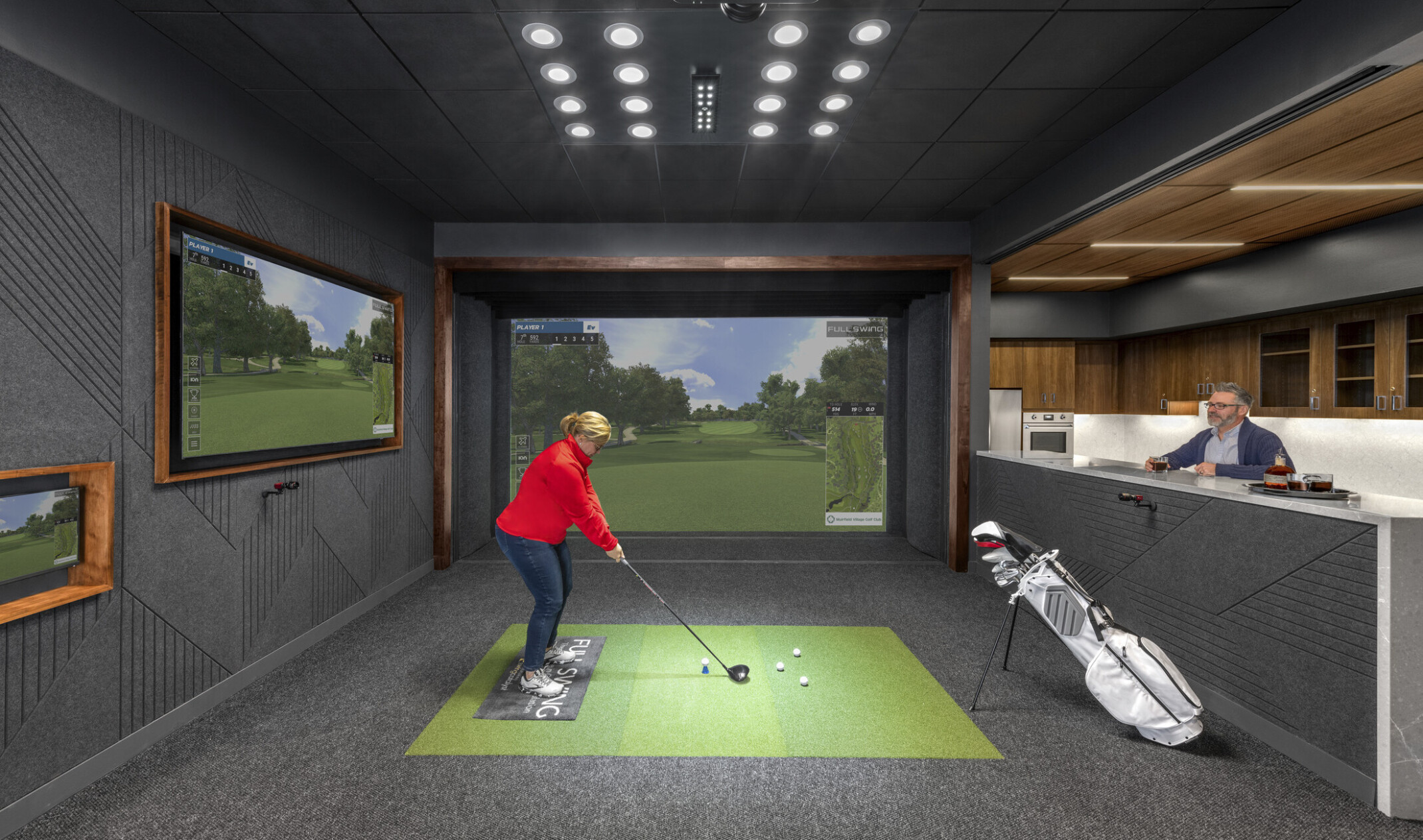 An indoor golf simulator with adjacent galley. Black room with wood accents