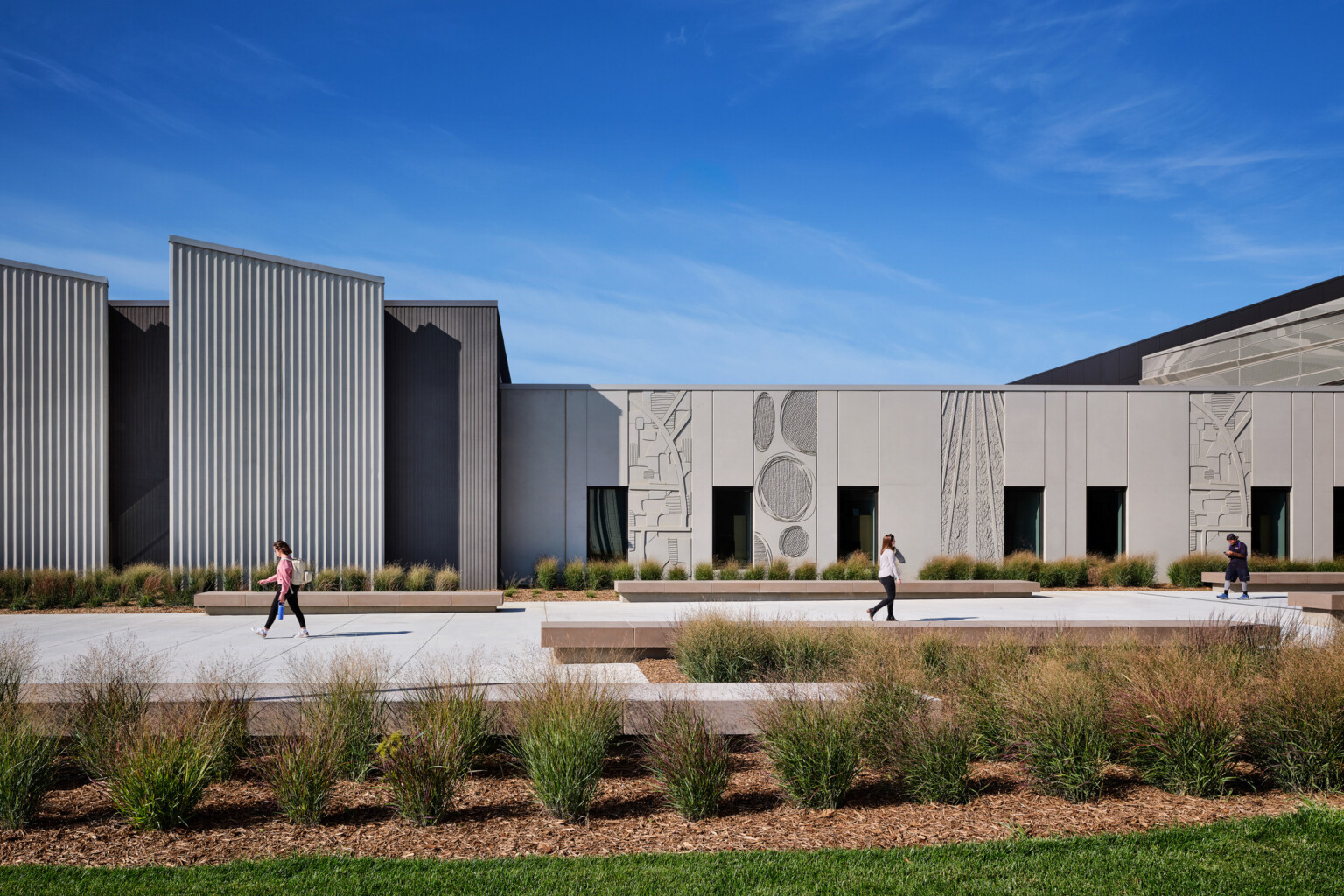 Beige colored single story building with shapes and artwork carved into the panels with modern angles