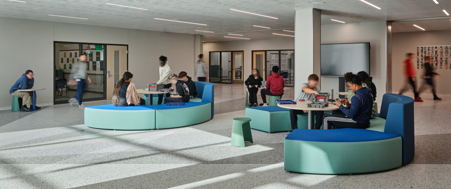 Open concept gathering area with blue and green modern seating filled with students