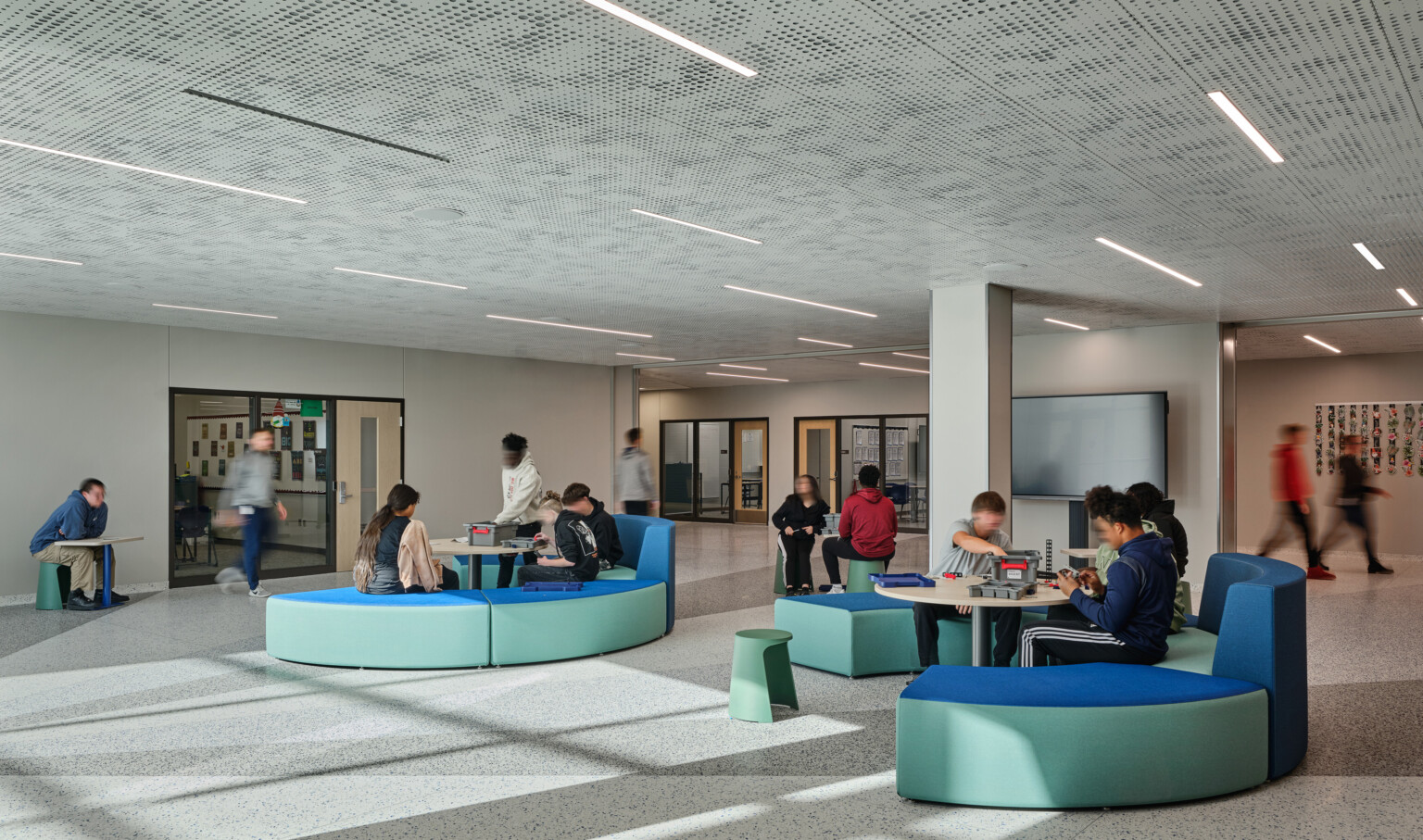 Open concept gathering area with blue and green modern seating filled with students