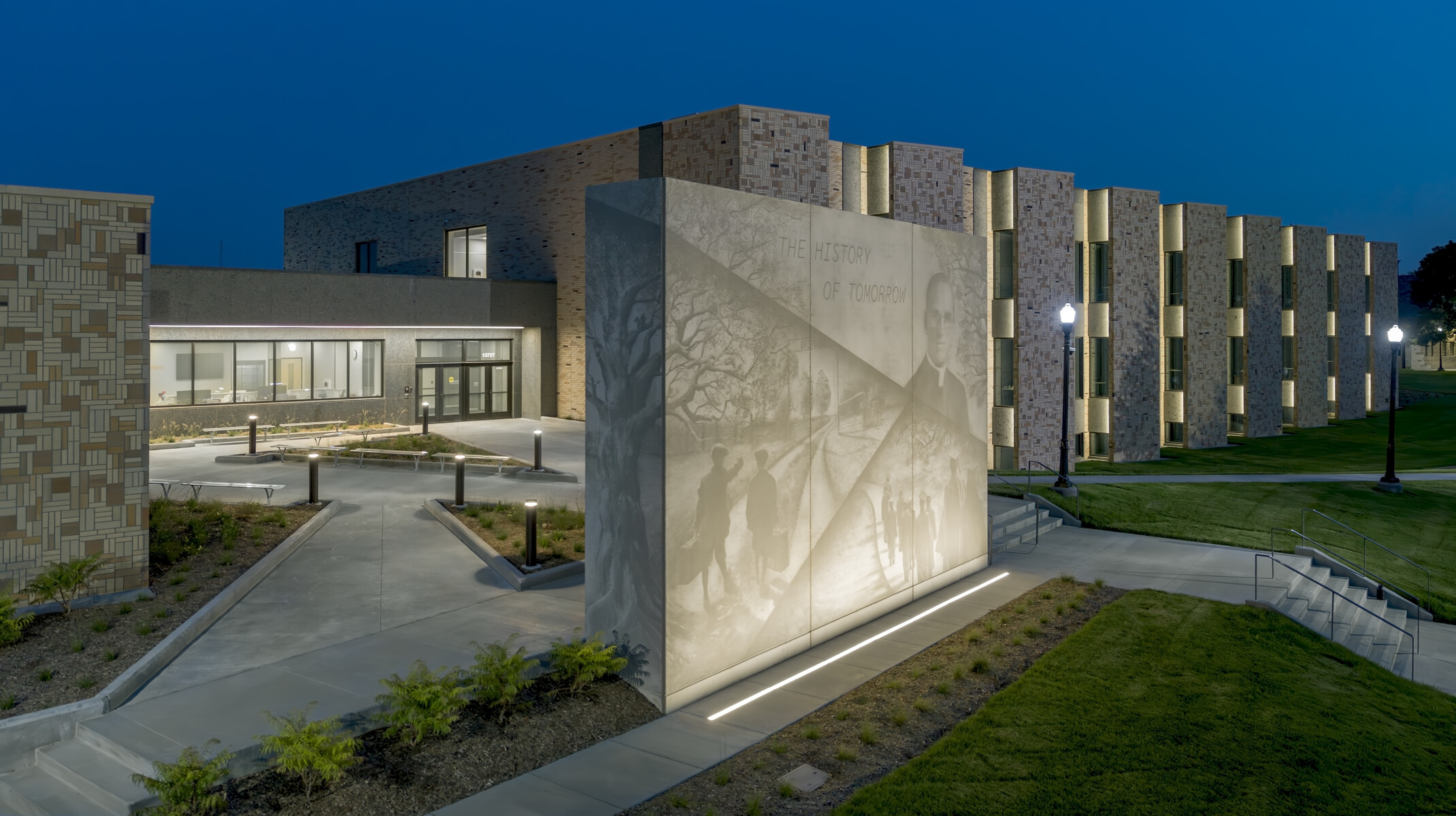 Nighttime rendering of a stone building with a mural light with phrase the history of tomorrow