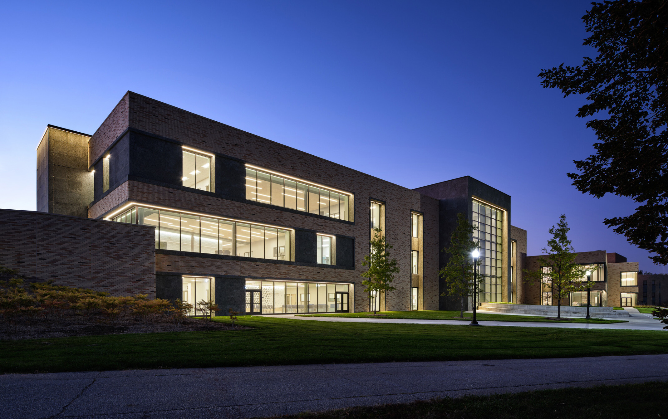 Nighttime shot of a multistory brick building showing windows filled with light