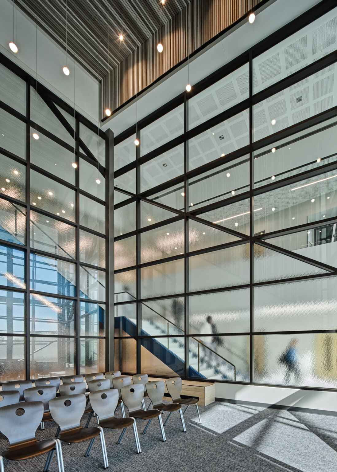 stairwell in Boys Town Education Center; stairs going down face large floor to ceiling windows; breakout space with chairs facing front lecture style