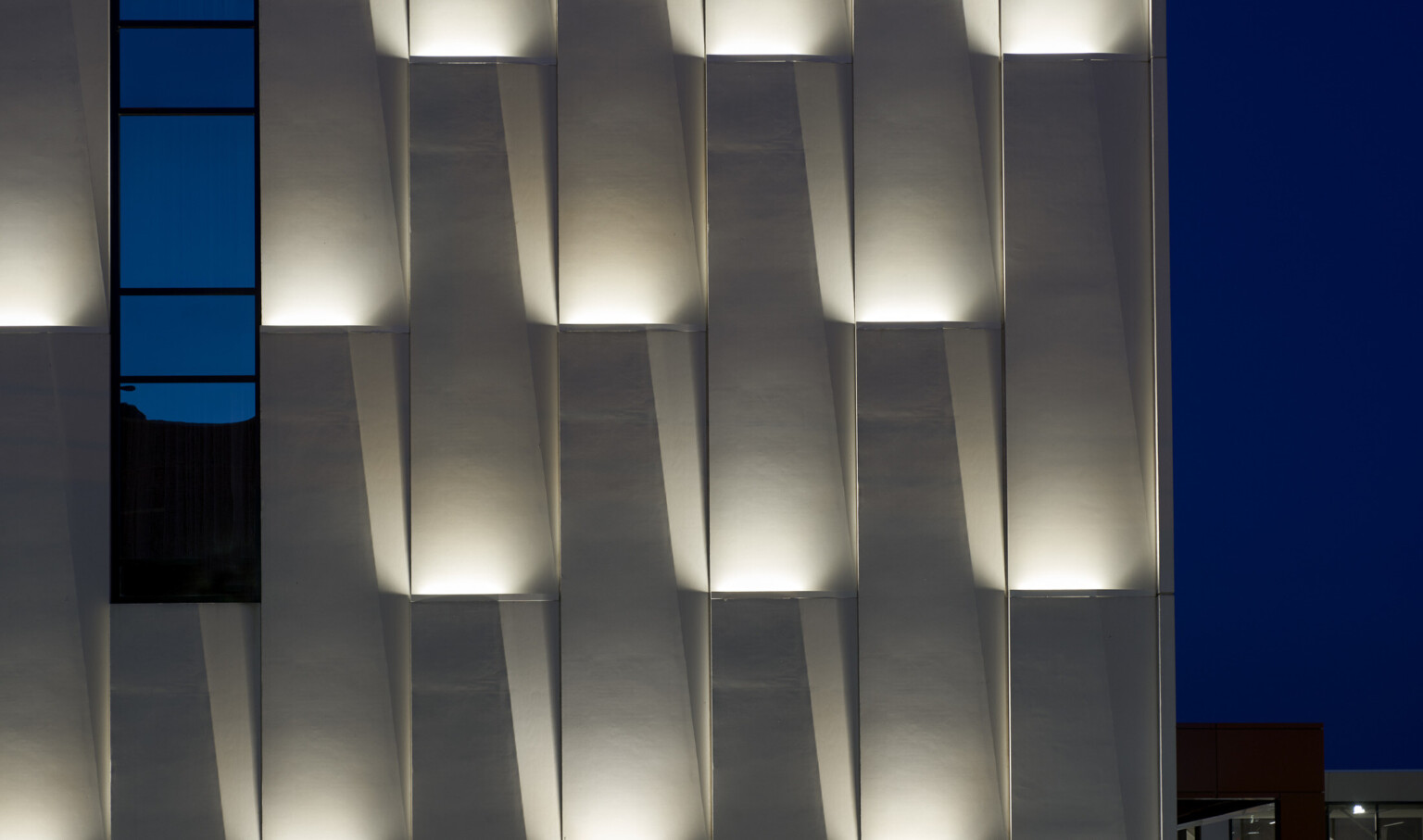 Panels in lifted wall grooves with recessed lighting illuminated at night