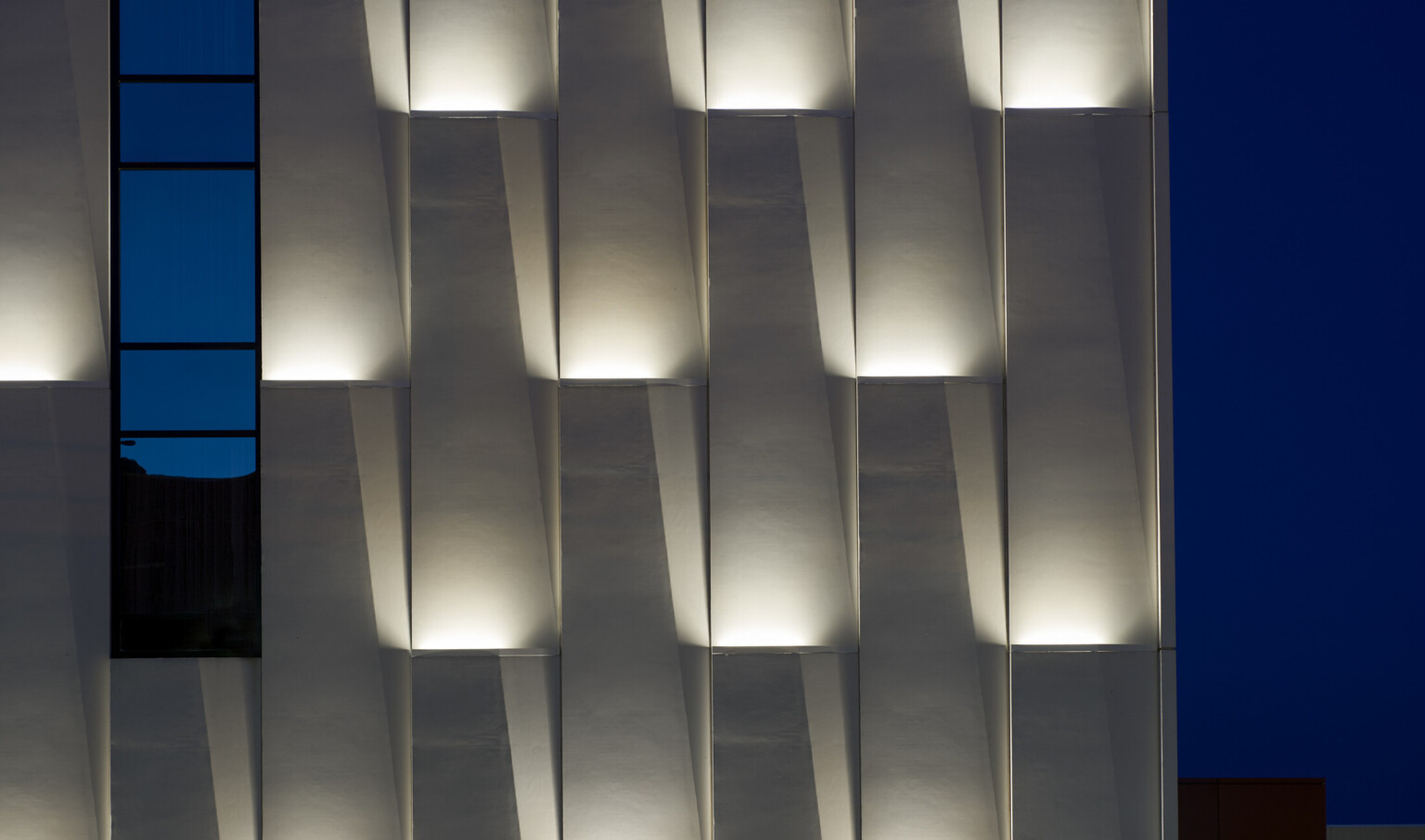 Panels in lifted wall grooves with recessed lighting illuminated at night