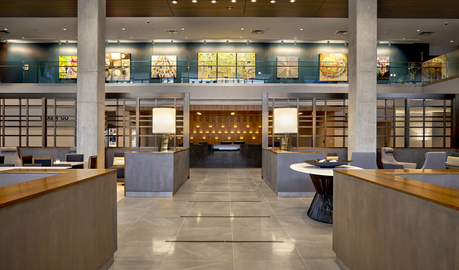 View down mezzanine hallway to reception desk. Wood panel wall mirrors texture of white exterior paneling, with lights at top