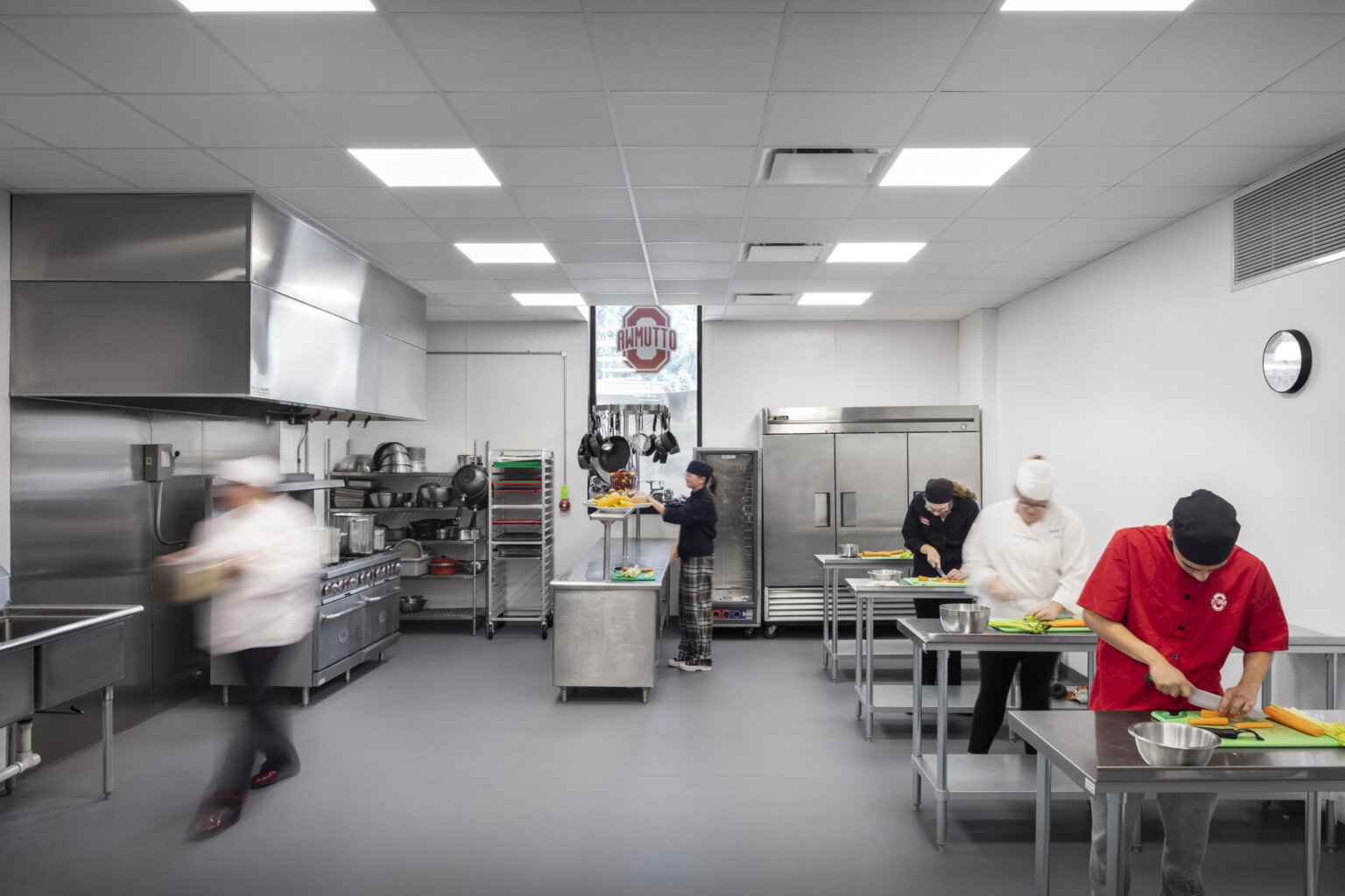 culinary arts lab in career center, students hone their knife skills on stainless work tables, walk-in refrigerator/freezer, florescent lighting