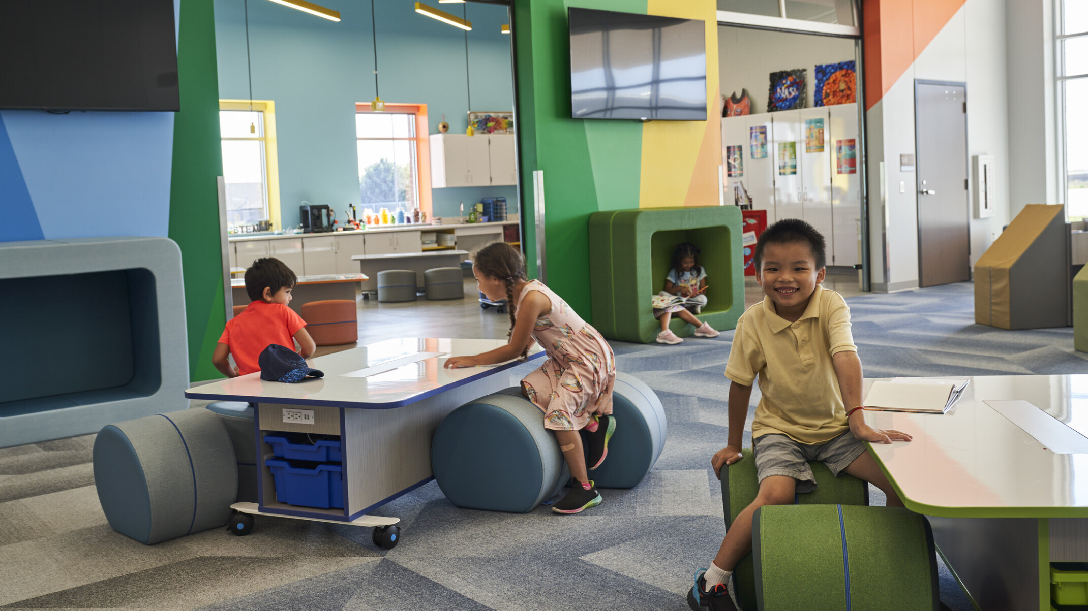 A colorful, modern classroom with children engaging with interactive furniture and books.