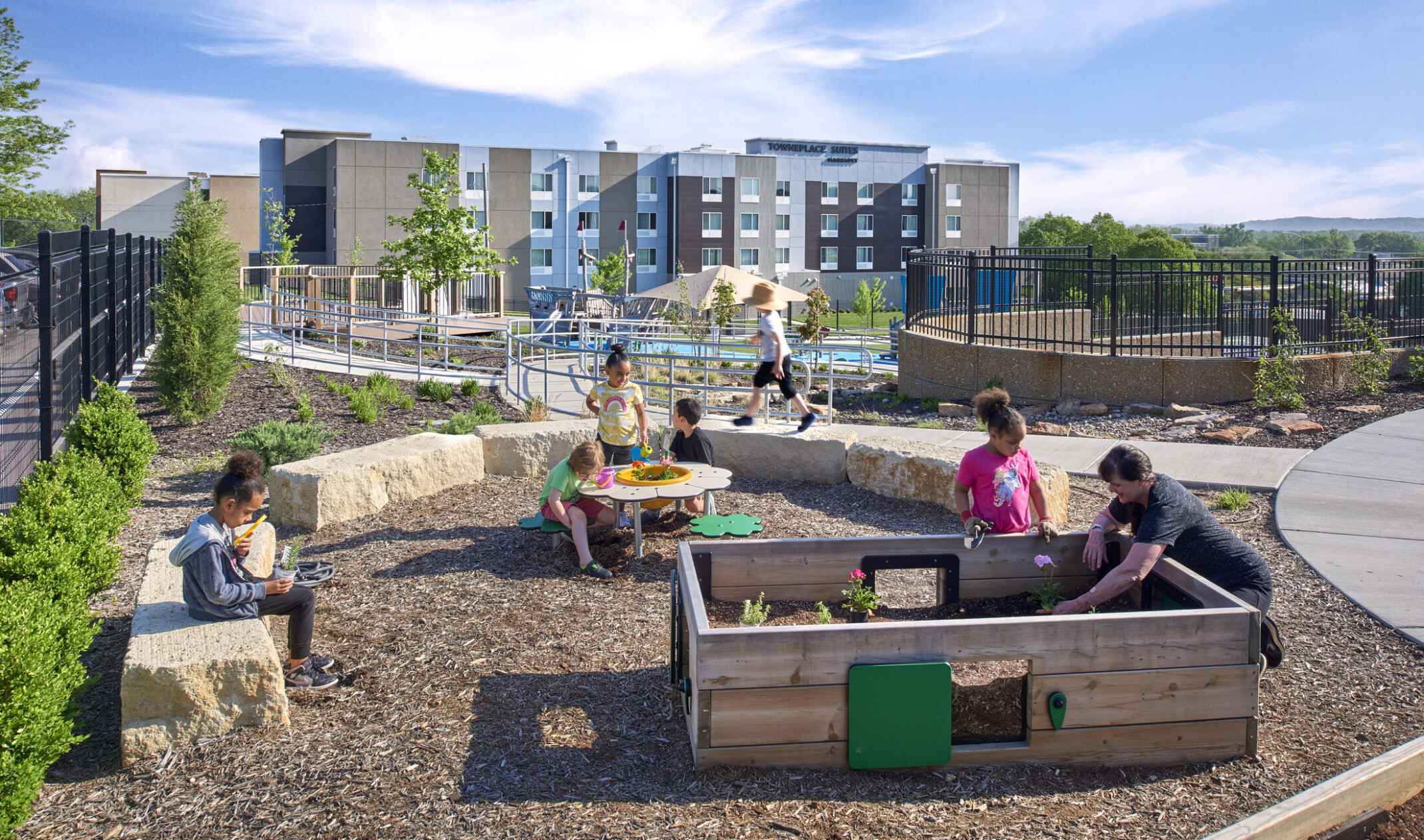 Children playing at a minimalist playground with benches and tables; small play structures