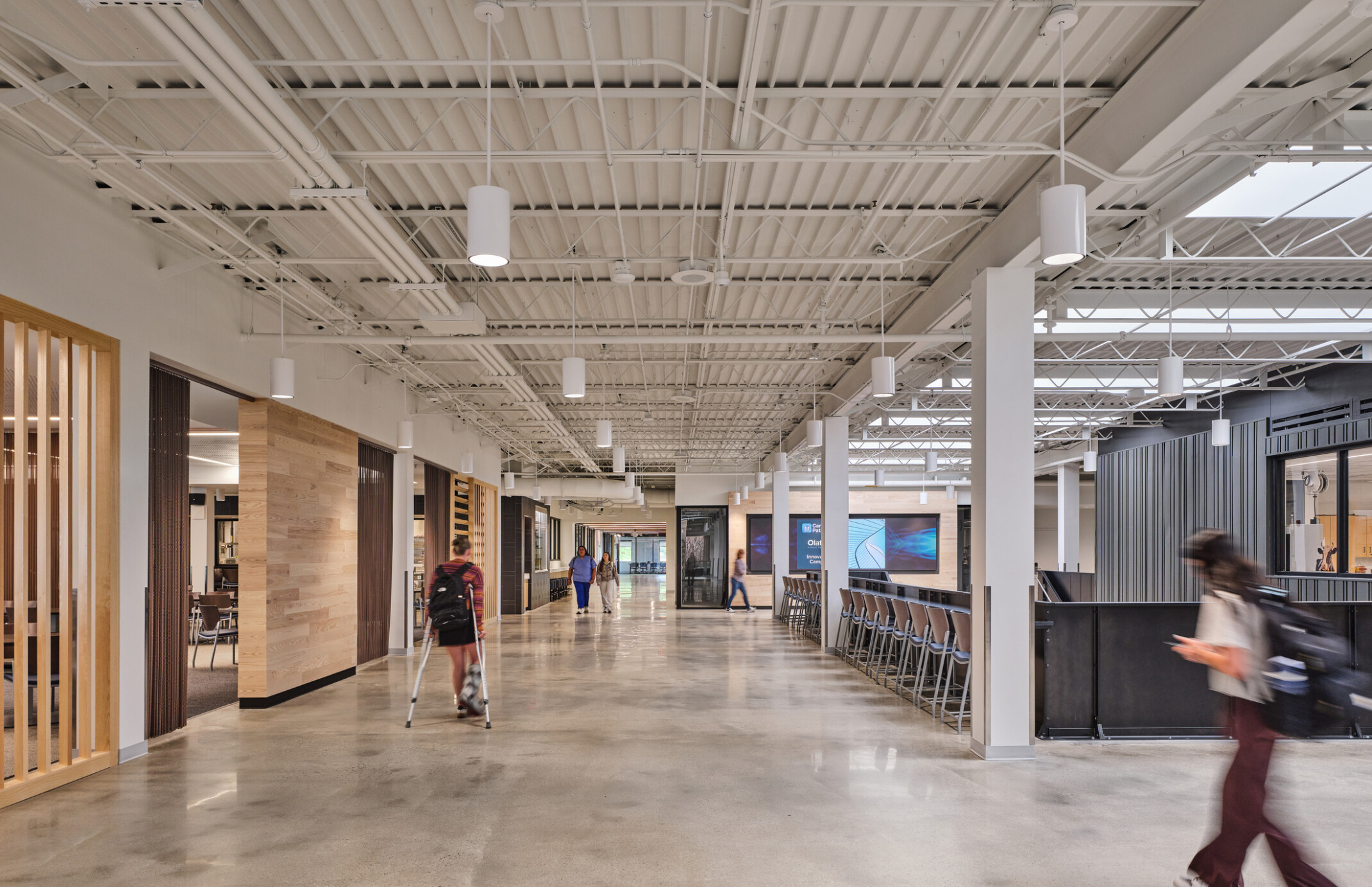 walkway in Olathe Innovation center with TVs on the wall and a communal seating space in the background