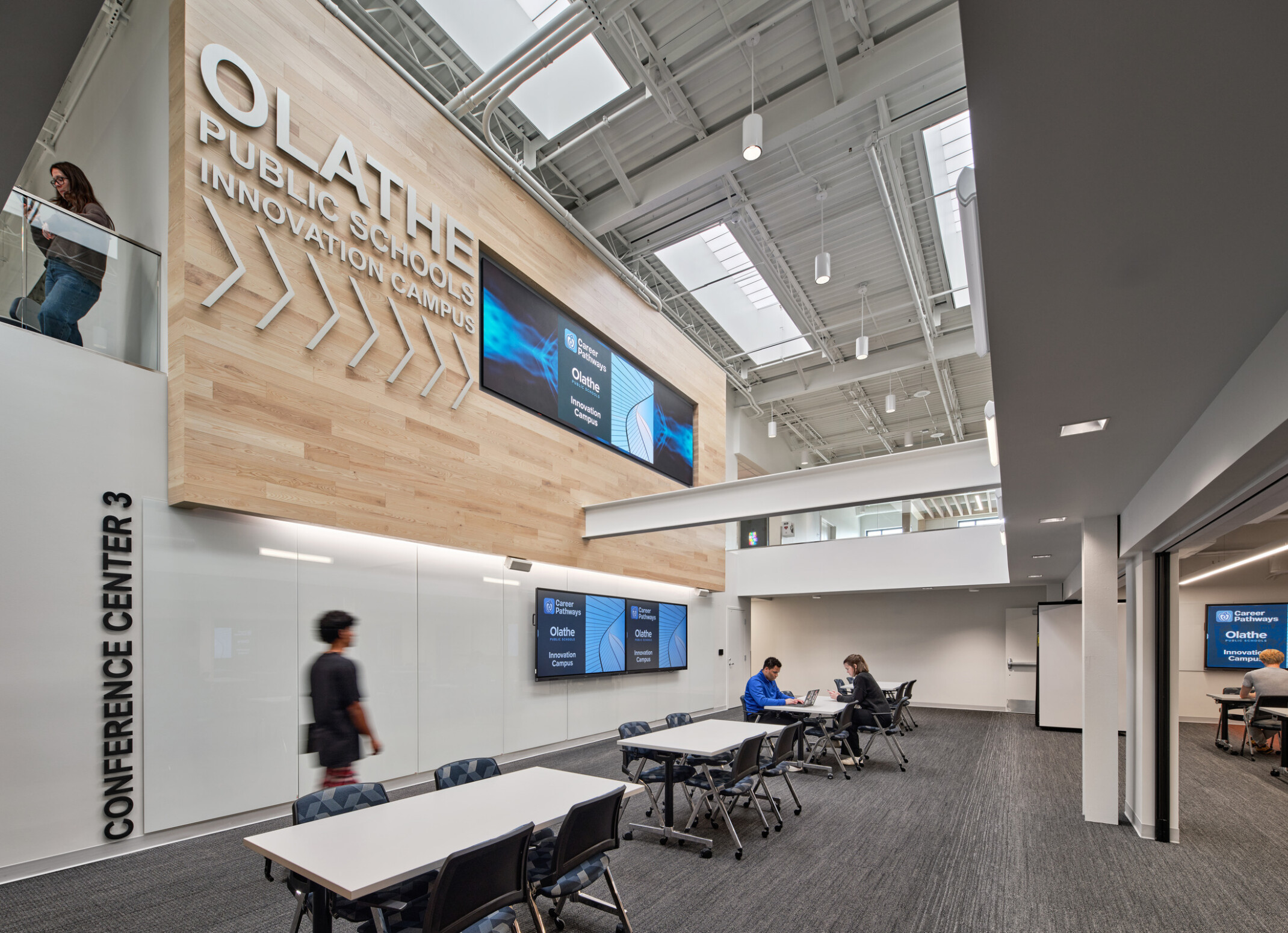 community study space in Olathe Innovation center with TVs on the wall and a communal seating space in the background
