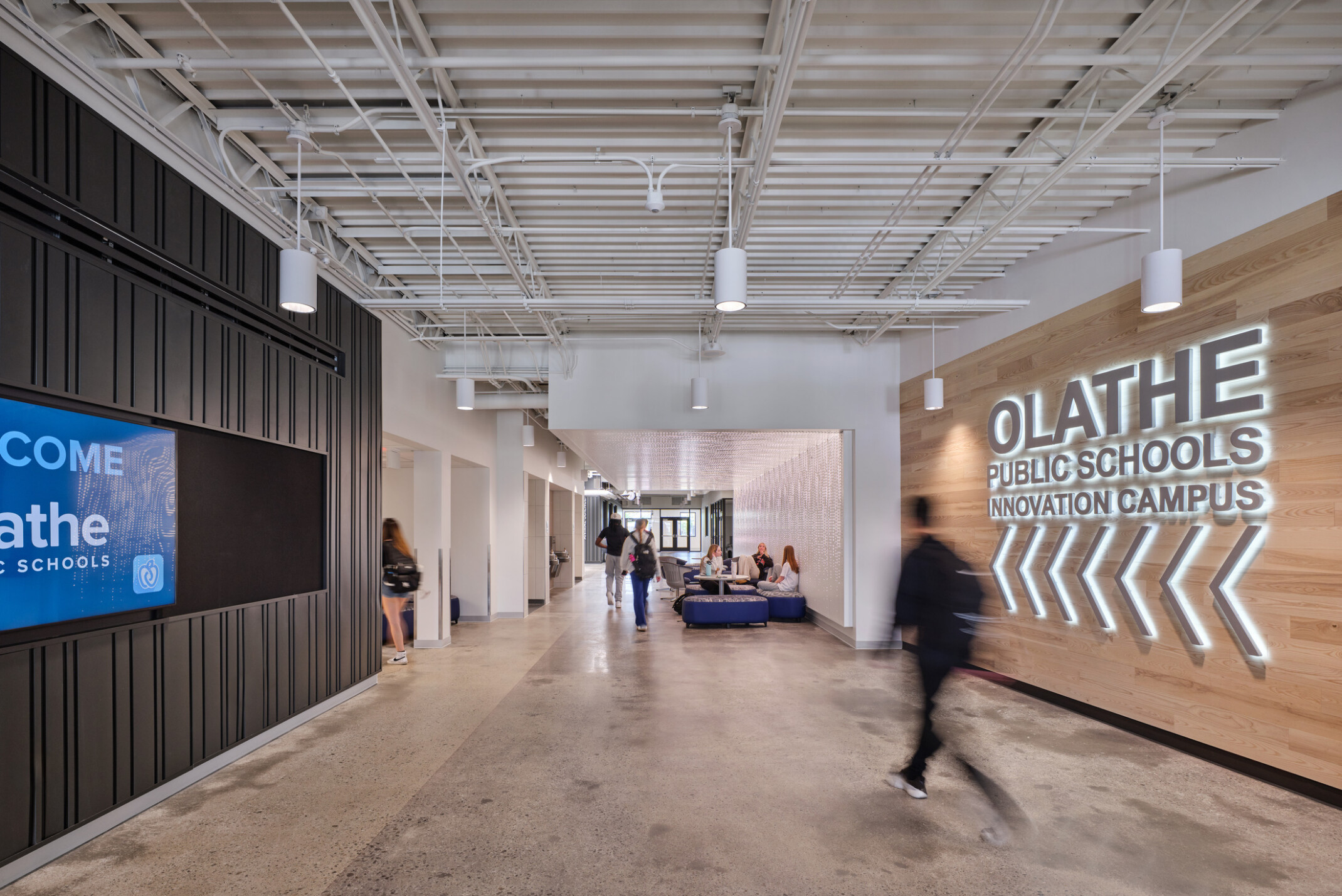 walkway in Olathe Innovation center with TVs on the wall and a communal seating space in the background