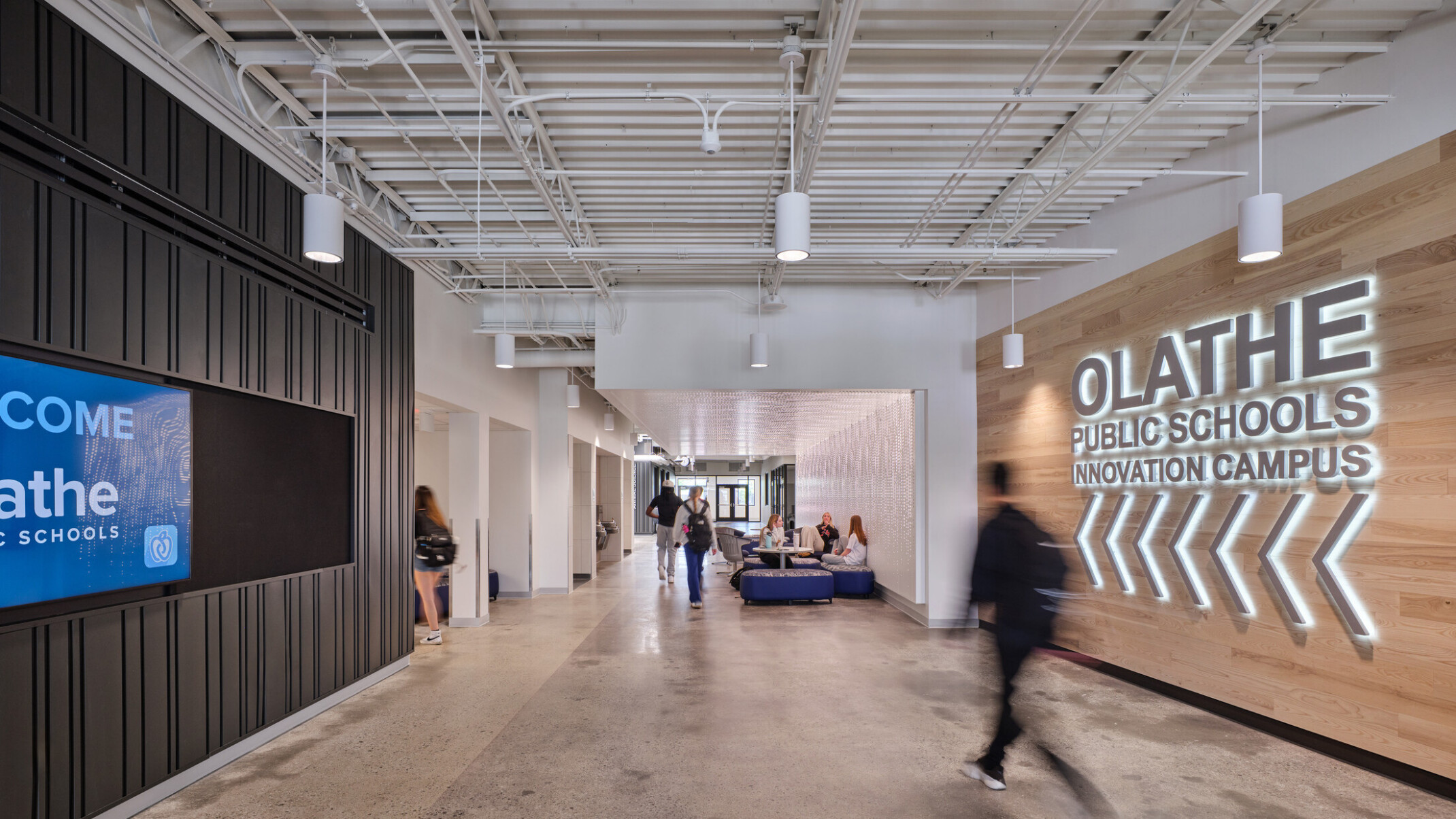 walkway in Olathe Innovation center with TVs on the wall and a communal seating space in the background
