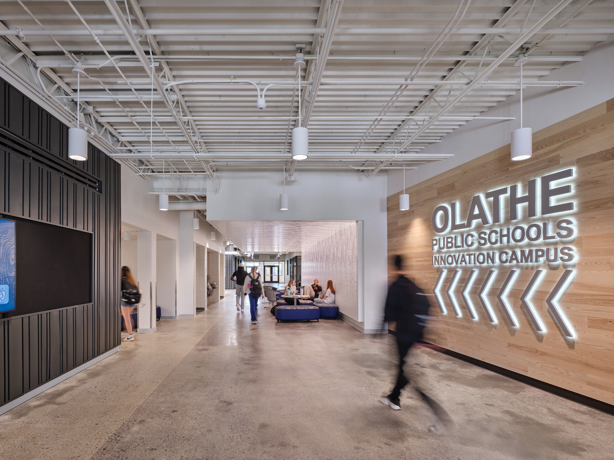 walkway in Olathe Innovation center with TVs on the wall and a communal seating space in the background