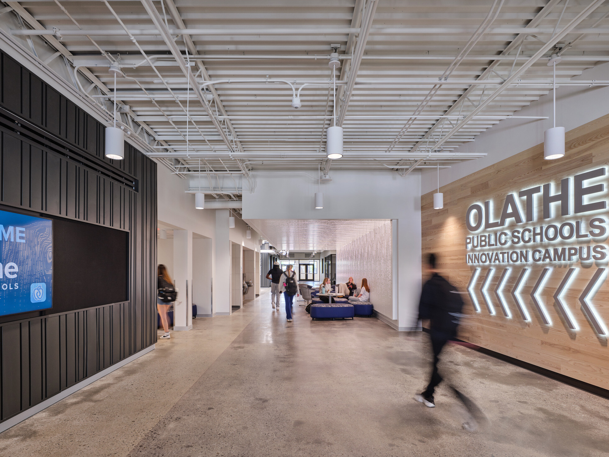 walkway in Olathe Innovation center with TVs on the wall and a communal seating space in the background