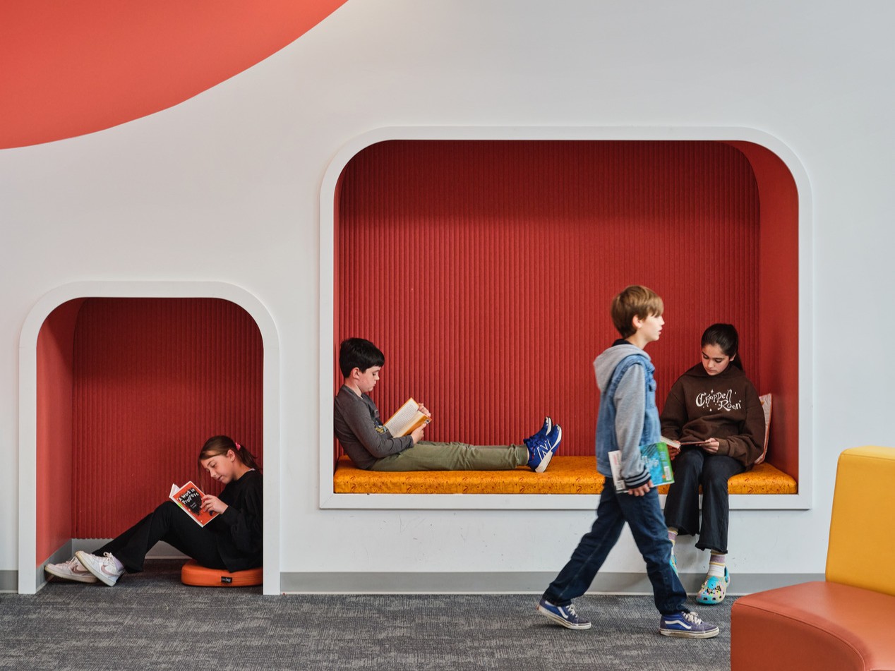 interior of a modern school community space with built in nooks for children to read and sit
