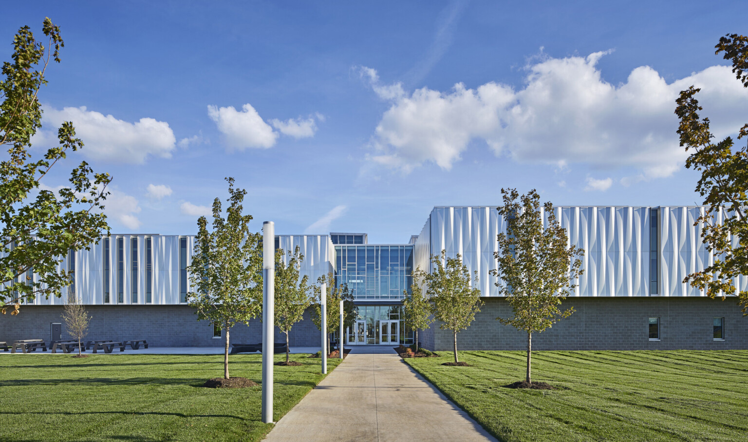Front view of building looking down a treelined path to the front entrance with 2 sets of glass double doors Front view of building looking down a treelined path to the front entrance with 2 sets of glass double doors