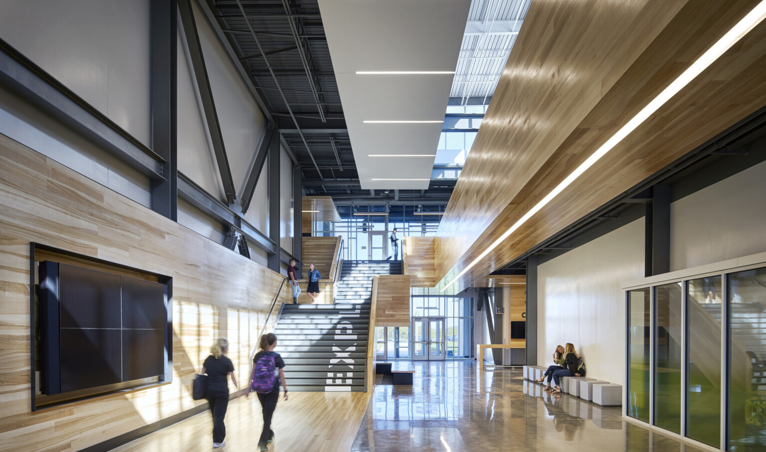 Missouri Innovation Campus interior hallway facing double height glass windows at entry and black staircase with wood walls
