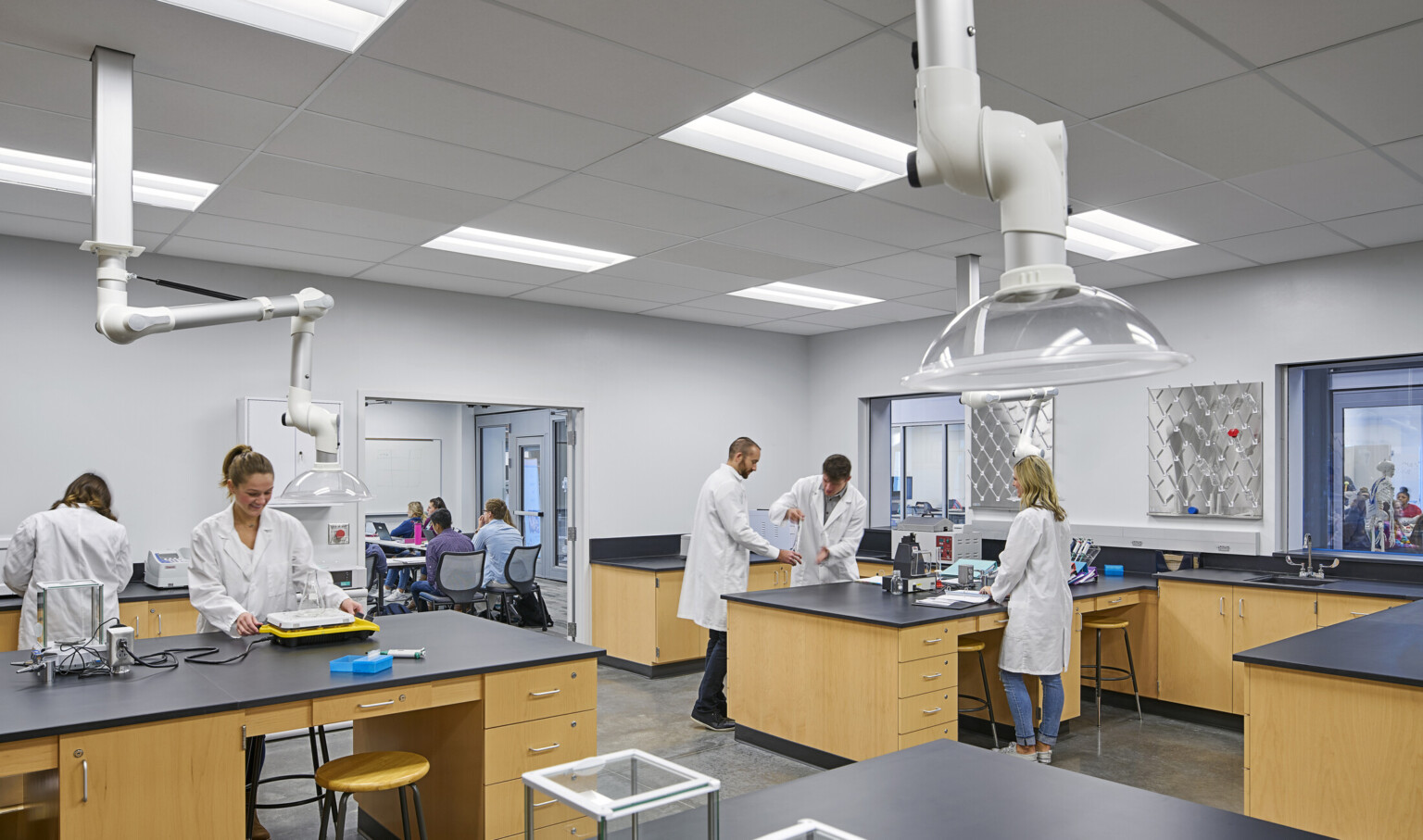 A group of individuals wearing lab coats, actively working on a project in a laboratory environment