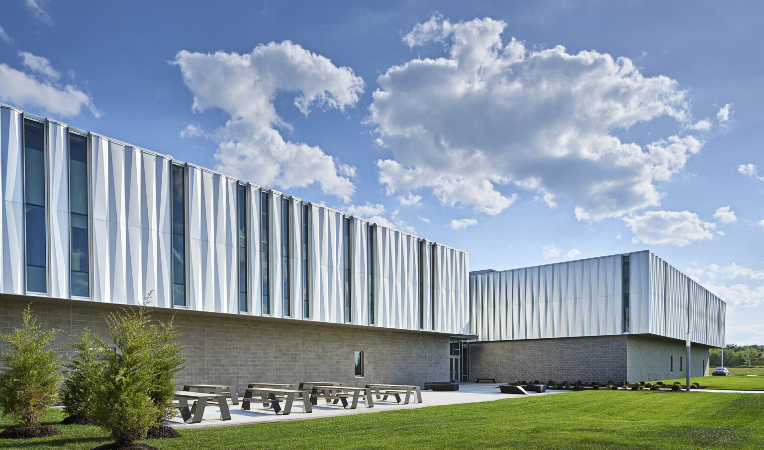 A metal building with a spacious lawn with an area filled with picnic tables