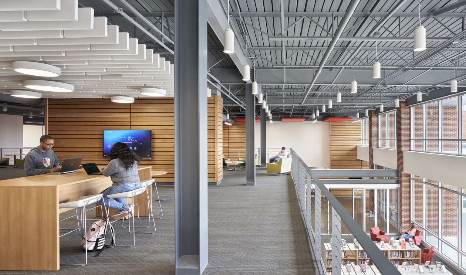 Seating areas on 2nd floor with wood panel accent walls overlooking 1st floor library. Double height windows on right wall