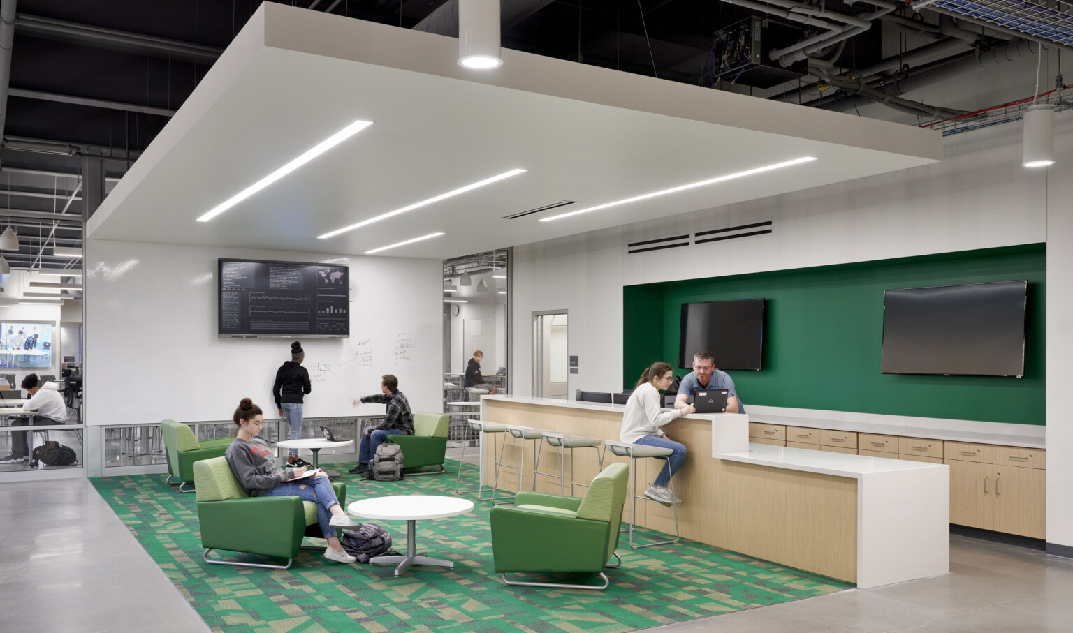 Room with white board wall and recessed light bars. Island and seating area. Green recessed wall detail, right, over counter