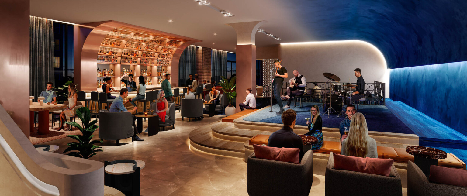 Bar in lobby section with curved roof, with blue carpeted stage opposite. Arm chair, bench, and bar seating available