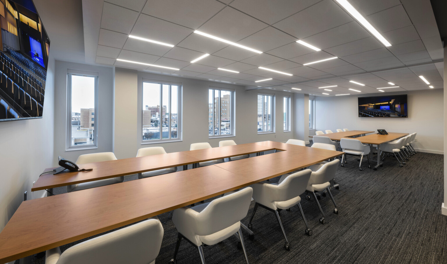 Indoor conference room with large, rectangular meeting room tables ad televisions
