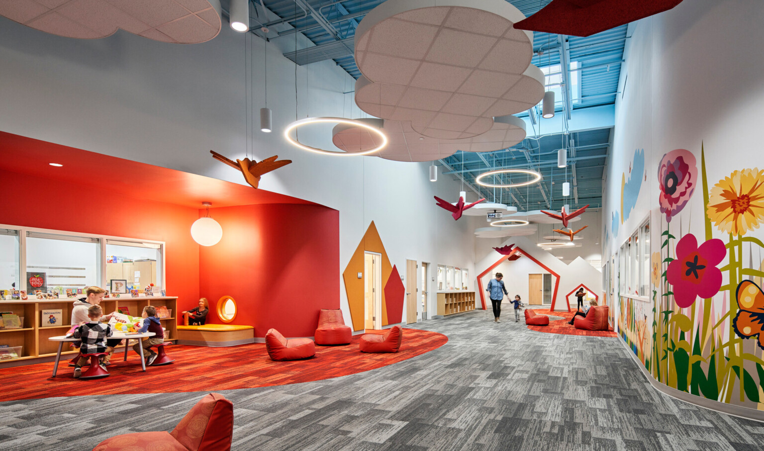 high blue ceilings and grey geometric print carpet with suspended cloud and orange bird elements, bright orange accent wall, mural with brightly colored flowers high blue ceilings and grey geometric print carpet with suspended cloud and orange bird elements, bright orange accent wall, mural with brightly colored flowers