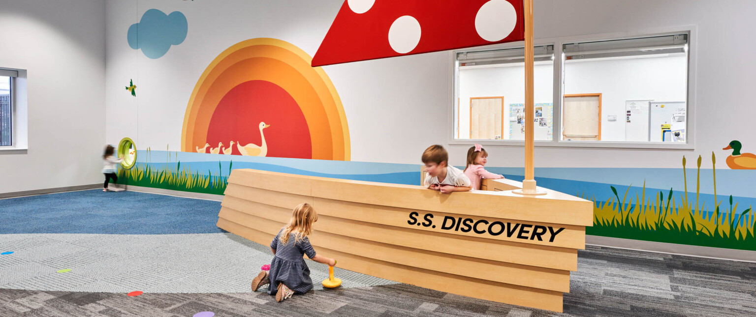 North Kansas City School Early Education Center interior. An interactive boat play area with red sail, graphic murals on wall