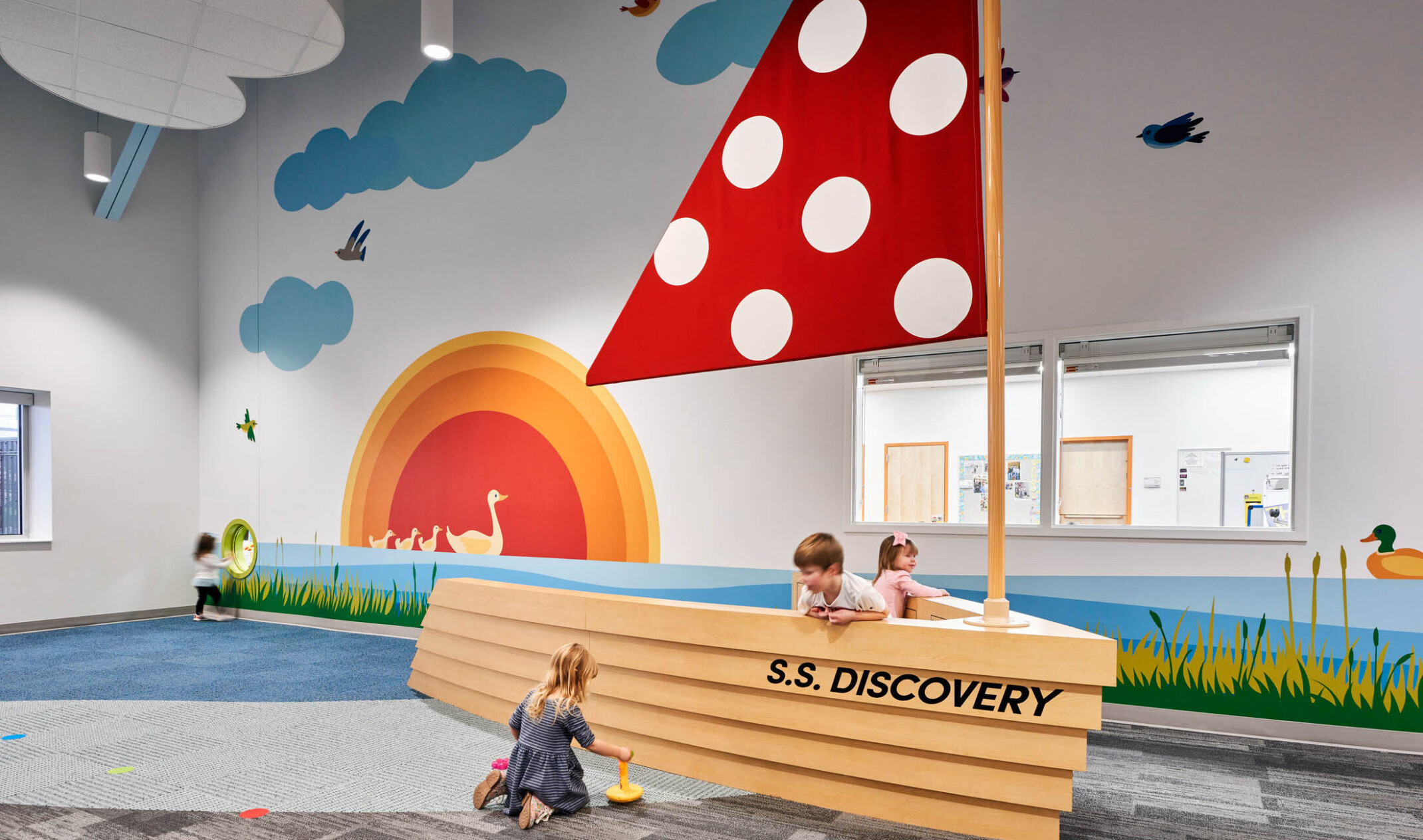 North Kansas City School Early Education Center interior. An interactive boat play area with red sail, graphic murals on wall