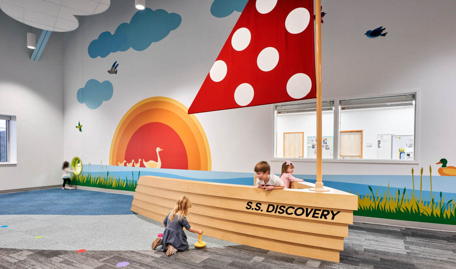 North Kansas City School Early Education Center interior. An interactive boat play area with red sail, graphic murals on wall