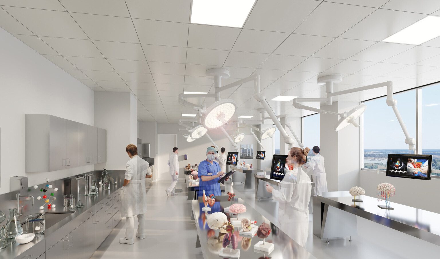Medical classroom with large circular lights and monitors suspended from the ceiling with models of human organs on tables