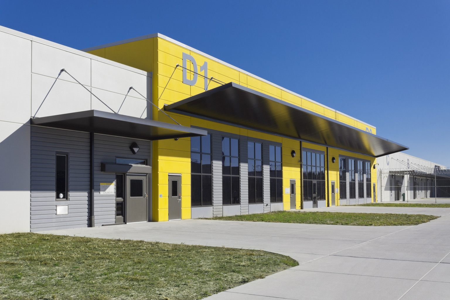 The Bledsoe County Correctional Complex exterior entryway D1. Yellow accent wall with silver awning next to silver panel wall